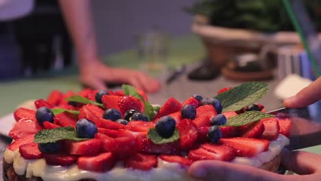 Close-Up-Woman-Cutting-Strawberry-Cheescake-At-Dinner-Table