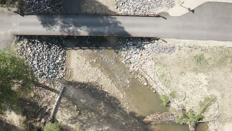 Aerial-drone-shot-of-a-slow-fly-over-bridge-and-creek-looking-straight-down