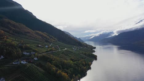 Lutro-farm-at-east-side-of-Sorfjorden-with-Oddan-in-the-end-of-the-fjord---Autumn-scenic-agriculture-and-landscape-clip-from-Ullensvang-Hardanger-Norway---Sunny-day-aerial-with-backlight