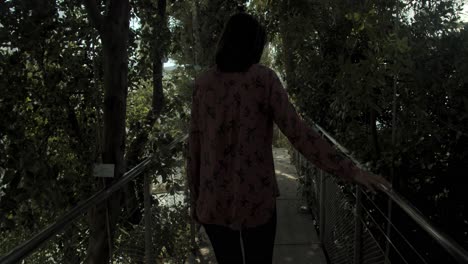 Young-woman-walking-through-a-beautiful-botanical-garden,-wide-shot-from-back,-slow-motion