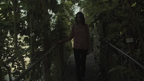 Young-woman-walking-through-a-beautiful-botanical-garden,-wide-shot,-slow-motion