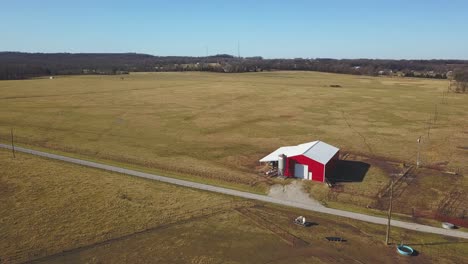 Low-altitude-aerial-view-of-small-barn-on-an-open-field