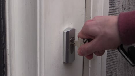 close-up-of-a-hand-putting-the-key-in-the-lock,-opening-the-door-and-entering-the-house