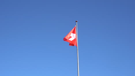 Die-Schweizer-Flagge-Weht-Am-Blauen-Himmel