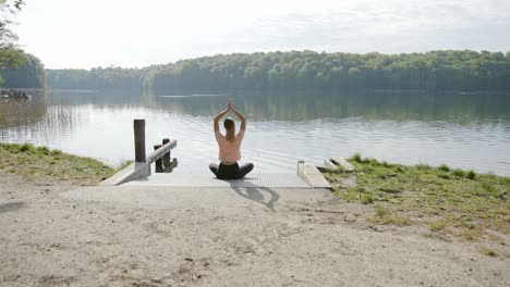 Woman-meditating-in-front-of-lake-on-sunny-day