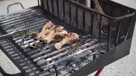 Hand-tong-turning-chicken-legs-on-barbecue-grill-static-side