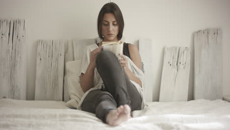Attractive-young-woman-reads-a-book-on-her-bed