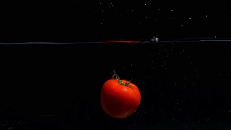 Kleine-Tomate,-Die-Vor-Schwarzem-Bildschirm-Ins-Wasser-Fällt