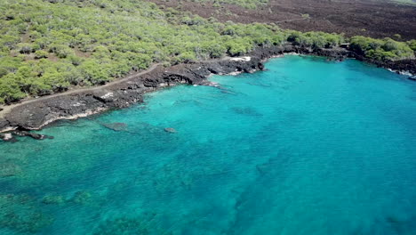 Kristallklares-Blaues-Wasser-Am-Schwarzen-Sandstrand-Auf-Big-Island-Hawaii-Mit-Lavagestein