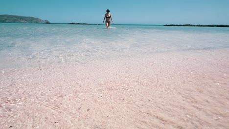 Girl-walking-out-of-the-sea-towards-the-pink-beach