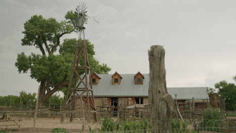 Western-farm-in-New-Mexico-with-wooden-windmill-rotating,-slow-motion