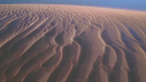 An-Einem-Hellen,-Sonnigen-Tag-Wird-über-Strukturiertem-Sand-Ein-Atemberaubender-Blauer-Ozean-Sichtbar