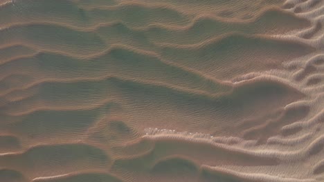 Ocean-water-rises-above-sandy-dunes-tops,-aerial-top-down-view