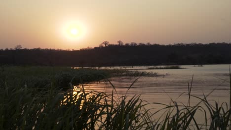 Wide-establishing-shot-of-the-sun-setting-over-a-river-in-Africa