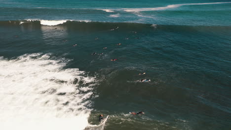 Aerial-drone-shot-of-people-surfing-and-trying-to-catch-waves
