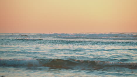 Wellen-Rollen-Am-Strand-Mit-Einem-Wärmenden,-Feurig-Orangefarbenen-Sonnenuntergang
