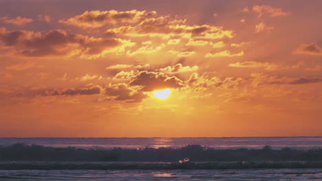Stunning-warming-orange-beach-sunset-with-dark-waves-rolling-into-shore