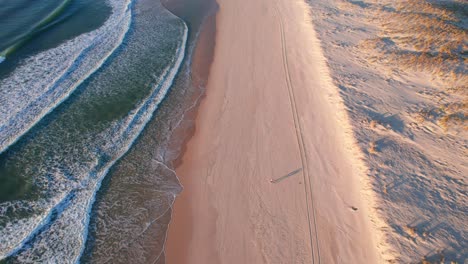 aerial-view-of-waves-coming-onto-shore,-sandy-beach-in-the-morning,-landes-france