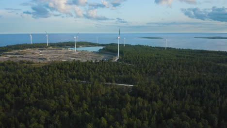 Aerial-shot-of-a-forest-and-a-coastline-with-wind-power-plants