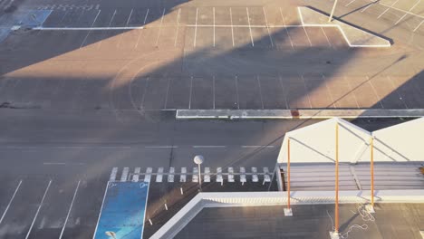 Empty-massive-parking-lot-near-shopping-building,-aerial-fly-over-shot