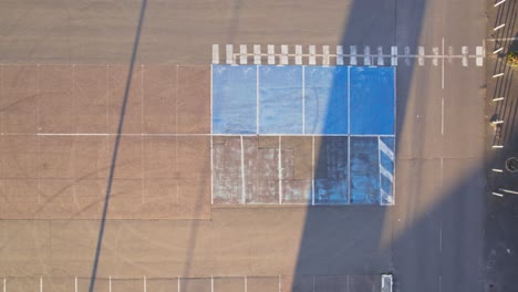 Blue-car-parking-spaces-for-disable-people-in-empty-parking-lot,-aerial-top-down-shot