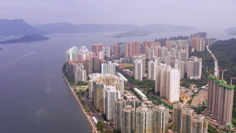 Multiple-boat-trails-at-sea-with-a-lookout-of-the-skyline-filled-with-colorful-skyscrapers-of-Ma-On-Shan-Hongkong-and-silhouettes-of-mountains-in-the-nature