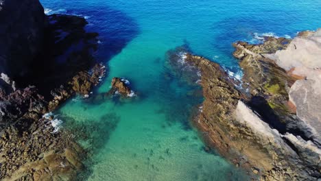 Crystal-clear-ocean-water-near-sandy-coastline-of-Lanzarote,-aerial-drone-view