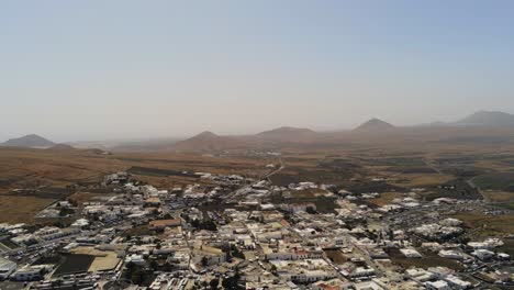 Desert-foggy-town-in-Lanzarote-with-mountain-landscape-in-background,-aerial-view