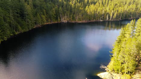 Drone-dolly-shot-of-a-bend-in-a-lake-with-the-reflection-of-the-sky-in-the-surface-of-the-water