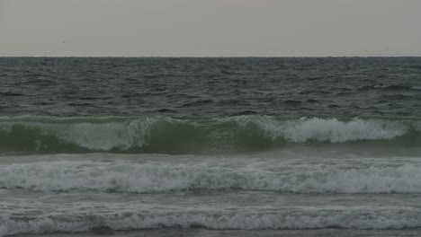 Ocean-waves-crashing-near-coastline-in-moody-dusk-time,-static-view