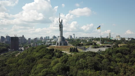 4k-Luftdrohnenaufnahmen-Des-Mutterlanddenkmals-Der-Ukraine-Zusammen-Mit-Der-Riesigen-Ukrainischen-Flagge-An-Einem-Bewölkten-Sommertag