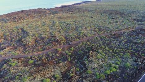 Lonely-vehicle-driving-off-road-near-coastline-of-Lanzarote-island,-aerial-view