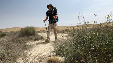 Low-angle-shot-of-a-hiker-walking-on-Mount-Ramon-desert-trail-on-sunny-day