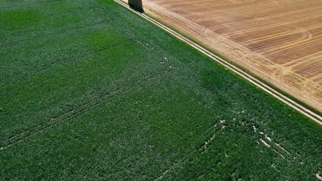 Stacked-hay-bales-on-the-side-of-empty-countryside-road,-drone-view