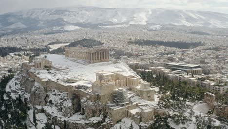 Aerial-view-away-from-the-snowy-Parthenon-temple,-winter-in-Athens,-Greece---reverse,-drone-shot