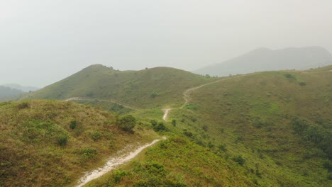 Expansive-white-gravel-path-between-the-hilly-green-low-vegetated-hills-of-Ling-Wui-Shan-Hill-in-Hong-Kong-China