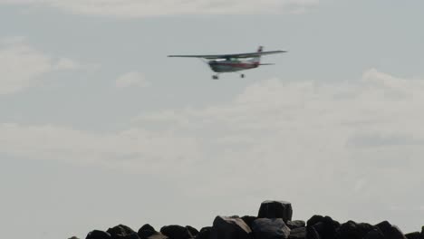 Small-biplane-landing-over-rocky-coastline-of-Amrum-island,-static-view