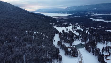 Frozen-icy-lake-surrounded-with-winter-forest-and-mountains