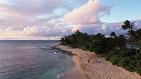 Tropical-paradise-of-sandy-beach-and-palm-trees,-Drone-flyover-Sunset-Beach-during-evening-in-Hawaii