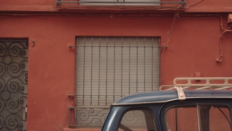 Vertical-Shot-Of-A-Small-Balcony,-Potted-Plants,-Car-And-An-Orange-Painted-Wall