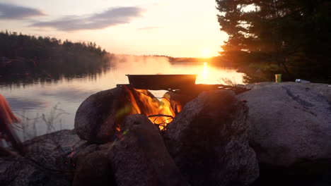 Food-is-cooked-over-a-campfire-next-to-a-lake-during-the-sunset