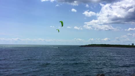 Amplia-Toma-Panorámica-De-Izquierda-A-Derecha-De-Dos-Kitesurfistas-Rozando-Las-Olas-Y-Mostrando-Sus-Cosas-En-El-Lago-Ontario