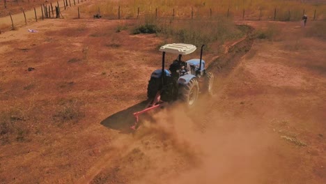 Drone-shot-panning-to-follow-a-farmer-using-a-tractor-to-till-a-dusty-dry-field-in-Bahia