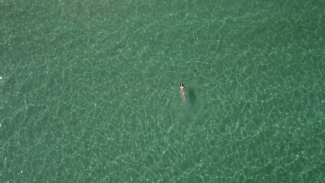 Rotating-drone-shot-of-a-beautiful-woman-swimming-on-her-back-in-the-Aegean-Sea