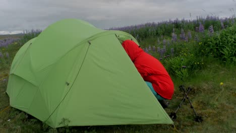 wild-camping-on-iceland,-hiker-leaving-a-green-tent-pitched-in-a-volcanic-landscape,-camera-movement,-camera-tracking-dolly-in-on-a-steadicam-gimbal-stabiliser,-wide-angle-shot