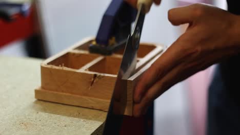 In-a-workshop-a-man-uses-a-Japanese-saw-to-saw-through-cherry-wood