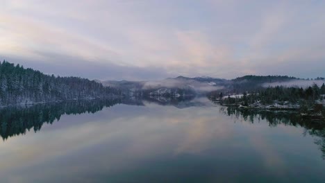 Aerial-view-of-winter-lake-with-reflection-and-fog-during-sunset