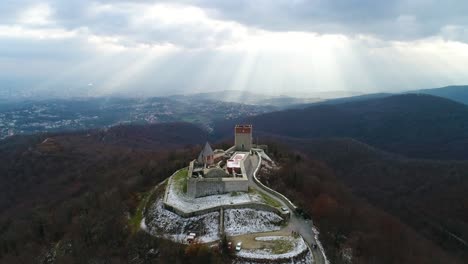 Aerial-view-of-castle-on-the-hill-with-town-and-light-rays-shining-in-the-background