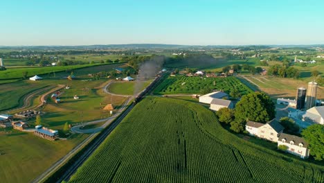 Steam-Train-Puffing-along-by-Amusements-in-Amish-Countryside-as-seen-by-Drone