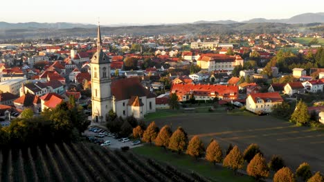 Aerial-Panorama-view-of-small-medieval-european-town-Slovenska-Bistrica,-Slovenia-with-church-and-castle-in-sunrise